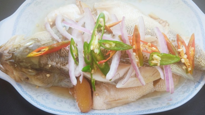 黄豆酱蒸鲈鱼,把洋葱细丝和辣椒圈均匀的铺在正好的鲈鱼背上。