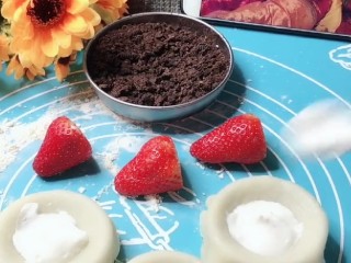 草莓雪媚娘,剂子擀成皮放在模具上，草莓切成4瓣，饼胚里放入淡奶油，最后放入草莓包好，再沾上炒熟的糯米粉