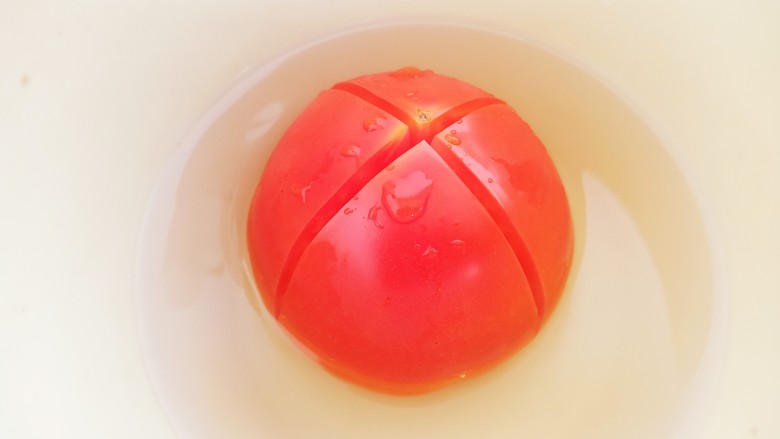 番茄鸡蛋面疙瘩汤,一个<a style='color:red;display:inline-block;' href='/shicai/ 3551'>西红柿</a>底部切十字花刀，用开水浸泡2分钟。