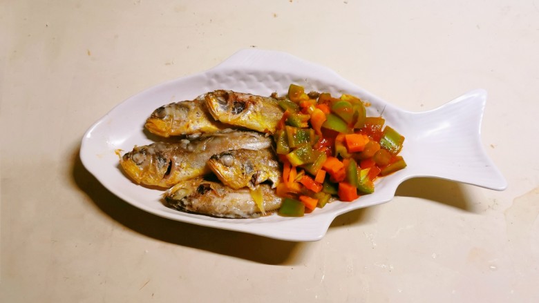 茄汁黄鱼,胡萝卜丁和青椒丁盛出放入鱼盘尾部。