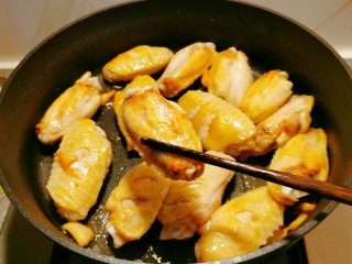 蒜香焖翅,起油锅放入食用油，码放好鸡翅，煎至两面金黄，出锅备用。