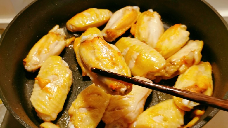 蒜香焖翅,起油锅放入食用油，码放好鸡翅，煎至两面金黄，出锅备用。