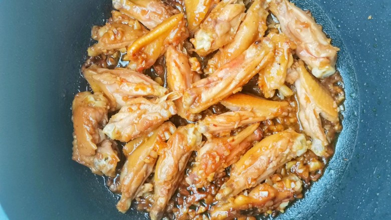 蒜香焖翅,将辣椒洗净切断，腌制好的鸡翅抹去蒜末,不粘锅倒适量油烧热，鸡翅下锅小火煎至金黄色，过程可以盖盖子焖一会儿