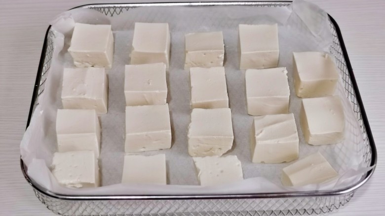 酸辣豆腐,豆腐摆在垫好油纸的烤网中。