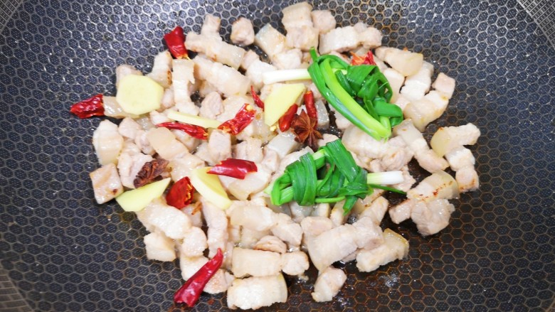 五花肉焖饭,下入小葱、生姜、干红辣椒和八角炒香。