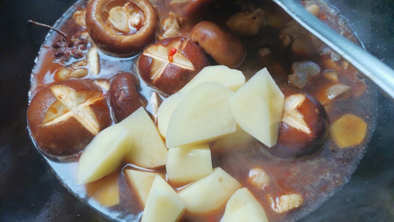 土豆香菇焖鸡,下入土豆翻炒均匀，盖上盖子焖煮10分钟至鸡肉土豆软烂