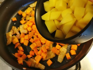 五花肉焖饭,放入土豆和胡萝卜丁翻炒。