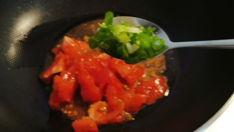 番茄海鲜饭,锅中留下底油继续加热，放入番茄翻炒，放入香葱增香。