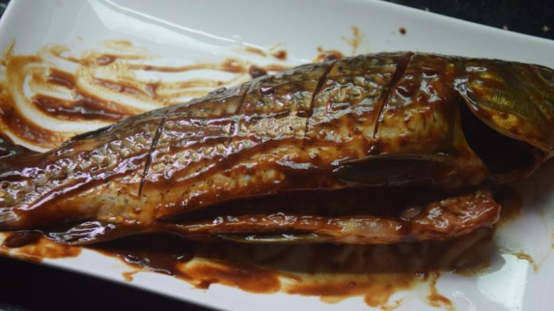 香烤鲫鱼,将酱料均匀地抹在鱼身鱼肚上