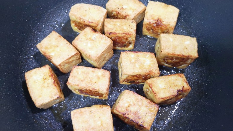 煎酿豆腐,将豆腐块六面都煎至金黄色。