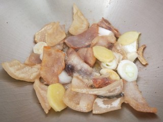 家常炖鲫鱼,锅中倒入适量油烧热倒入猪皮炒黄在加入葱姜蒜炒香。