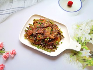 韩式烤五花肉,盘子里铺上吸油纸，底部垫上煎好的豆角，再放上煎好的五花肉。 