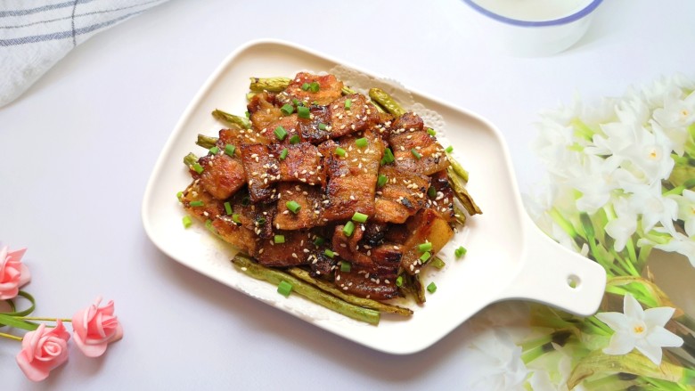 韩式烤五花肉,盘子里铺上吸油纸，底部垫上煎好的豆角，再放上煎好的五花肉。 