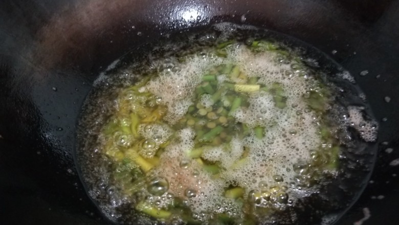 蒜苔香干,锅中倒入适量油烧热，蒜苔过一下油。