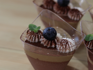 巧克力咖啡慕斯杯,表明挤上奶油后，还可以用水果装饰下，再过筛一层薄薄的巧克力粉