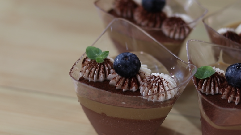 巧克力咖啡慕斯杯,表明挤上奶油后，还可以用水果装饰下，再过筛一层薄薄的巧克力粉