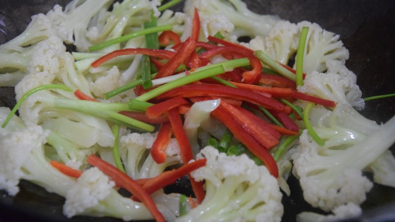 椒盐花菜,倒入红椒丝和葱段，翻炒至变软