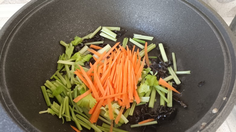 芹菜木耳炒肉丝,木耳发出啪啪声后，放入芹菜和胡萝卜，翻炒两分钟；