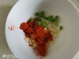 凉拌蒸茄子,蒜切成蒜末，葱切成葱花，装入碗中，加入一勺辣椒面