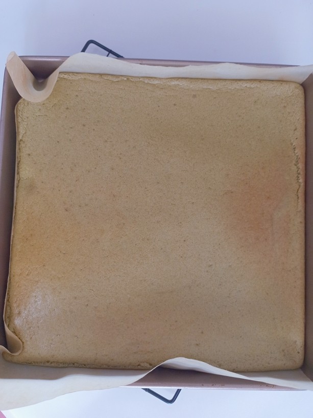 抹茶红豆蛋糕卷,把烤好的蛋糕取出来，上面盖上一层油纸翻过来