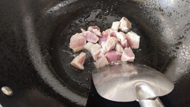 白萝卜炖猪肉,锅里的冰糖融化后，看上去有点焦黄时倒入猪肉块煸炒，炒制变色