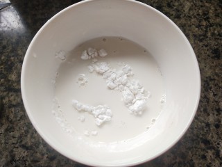椰丝牛奶小方糕,碗里倒入玉米淀粉，再倒入80ml牛奶，混合均匀。