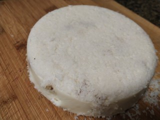 椰丝牛奶小方糕,把容器里的牛奶椰丝倒扣在砧板上，切成小块