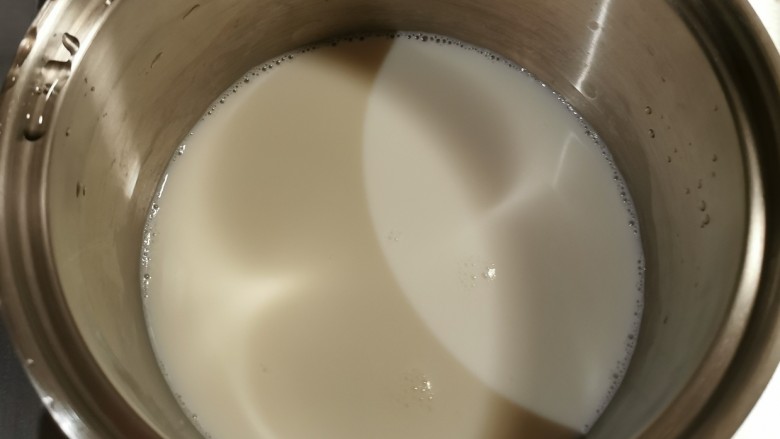 椰丝牛奶小方糕,牛奶倒入奶锅加热。