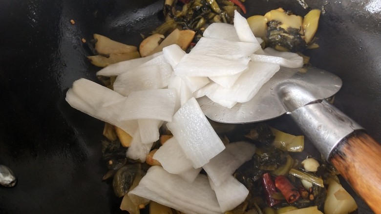 酸菜海鲜锅,腌制好的萝卜片拧干水分，放入锅里和酸菜一起炒
