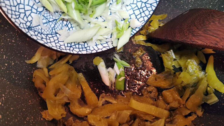 酸菜海鲜锅,酸菜帮子煸干后加入少许油爆香姜片与青蒜苗后取出备用