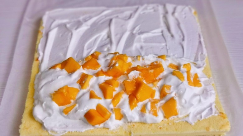 果子蛋糕,将奶油馅均匀涂抹在蛋糕上，再放上切好的芒果块。