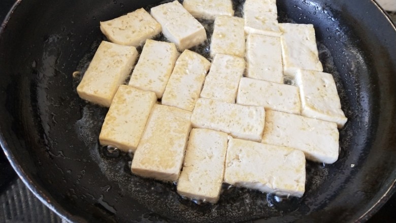 韩式辣酱豆腐,锅里放油烧热，把切成片的豆腐依次摆入锅中，煎至两面金黄