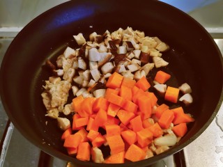 香菇板栗焖饭,放入胡萝卜丁和香菇丁翻炒。