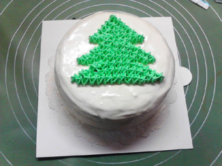 圣诞树蛋糕,将绿色奶油装入带有尖齿花嘴的裱花袋中，将圣诞树主体的轮廓挤满。