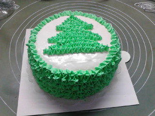 圣诞树蛋糕,再用绿色星形，从斜面的上边缘到蛋糕的底边，将整个侧面填满。