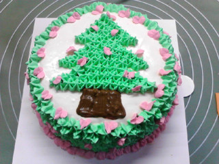 圣诞树蛋糕,最后将剩下的糖和红色色素加入剩下的淡奶油中，打出粉红色奶油，用叶形花嘴在绿色外圈的内侧间隔挤上两片相对的叶片，圣诞树上也点缀几颗。