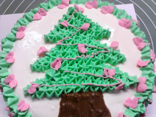 圣诞树蛋糕,最后换用细裱袋，在圣诞树上拉出粉色的细丝彩带。