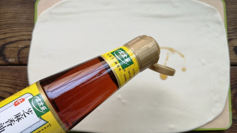 豆角焖卷子,将醒好的面面团擀成薄片状，再面片表面均匀抹一层芝麻香油。