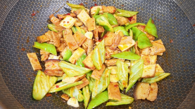 辣椒豆腐干小炒肉,下入蒜片和青椒翻炒均匀。