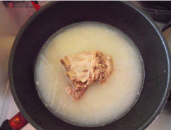 一品蘑菇煲,煮够时间后掀开锅盖，汤已经变得乳白了，下入生姜片。继续煮5分钟后捞出肋排，留下白汤。
