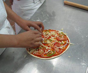 意大利风味比萨,然后将少许的奶酪放在抹好比萨酱的饼皮上,是为了防止烤好的比萨那起来的时候原料脱落
