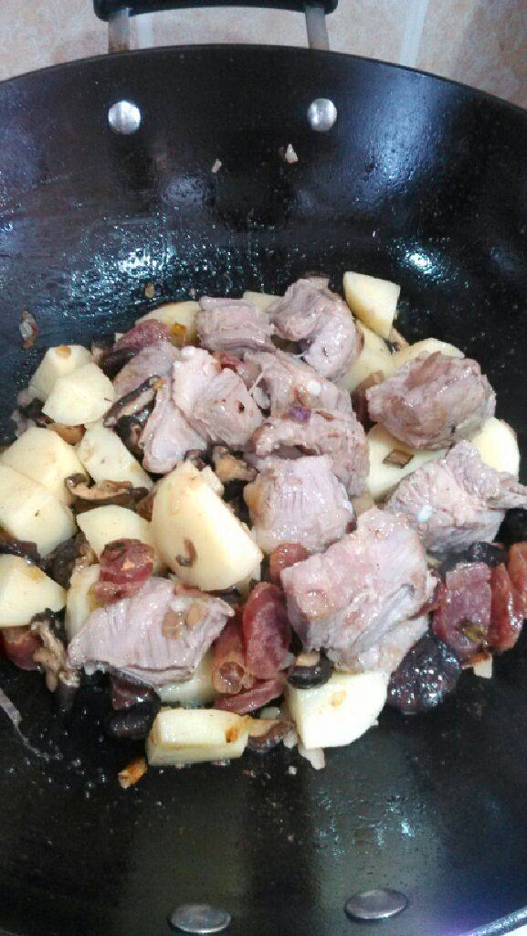香菇土豆排骨饭,将腊肠先入锅煸出油，再放入香菇煸香，继续放入土豆和排骨煎炒。