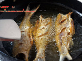 香辣刁子鱼,腌制好的鱼取出，用厨房纸吸干鱼生和鱼腹的多余水分。油锅大火高温下鱼炸定型后转小火慢炸，捞起沥干油后在反复回锅小火复炸2次，炸过3边后，捞起沥油备用。