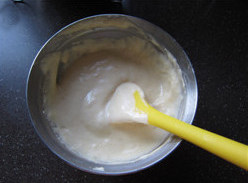 酸奶果仁小蛋糕,换橡皮刮刀，取一部分面糊，加入到混合液体中；切拌均匀