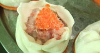 鲜虾烧卖,取一张<a style='color:red;display:inline-block;' href='/shicai/ 4346'>饺子皮</a>放在功夫茶杯上（也可放在手心），放入适量虾肉馅，将收口慢慢收拢，上面放点蟹子或青豆做装饰，将做好的鲜虾烧卖放在红萝卜片上。