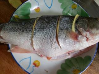清蒸剁椒鲈鱼,在鱼身上偏几刀，夹姜片。