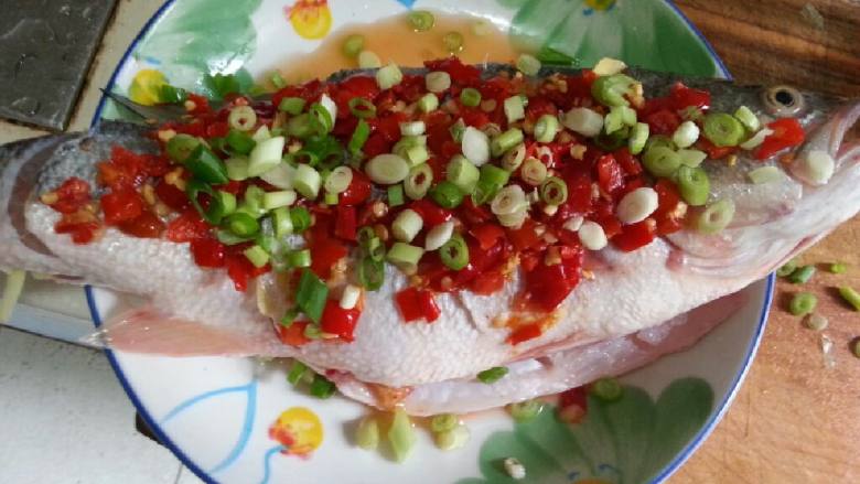 清蒸剁椒鲈鱼,鱼身上放剁椒和葱花。