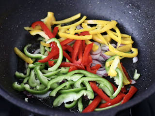 彩椒鸡肉孜然小炒,加入黄、红、绿椒丝，大火快速翻炒均匀。