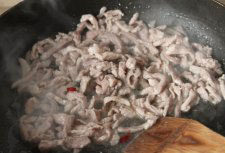榨菜炒肉丝,用勺子将肉丝快速滑散炒至变色，放入洗净切段的红辣椒