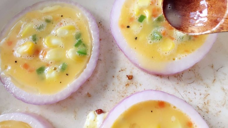 洋葱圈煎蛋饼-可以和宝贝抢着吃的美食,用勺子将鸡蛋液舀入洋葱圈内，注意不要放太满，齐平或九分满即可，煎的过程中鸡蛋液会稍稍膨胀，太满溢出影响最终成品颜值哈。